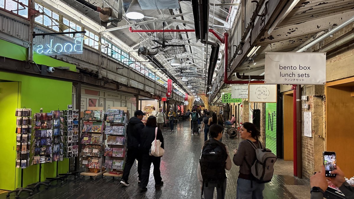 Interior view of Chelsea Market in NYC, showing shops, food, and visitors.