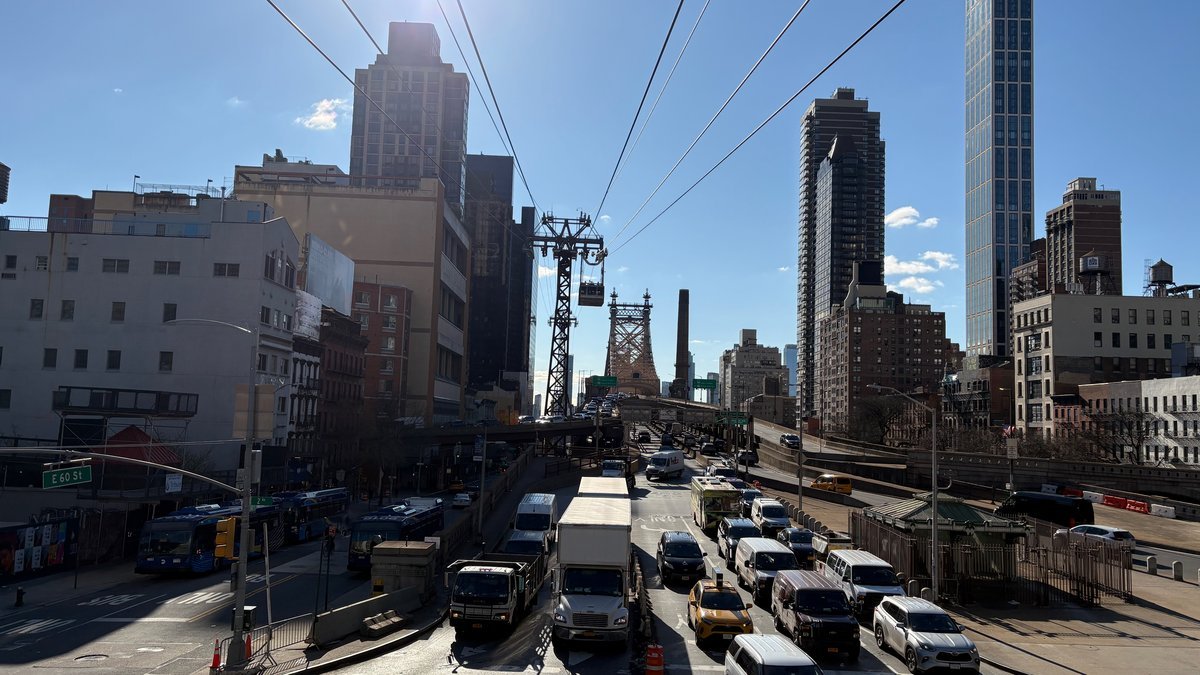 Roosevelt Island Tramway and Queensboro Bridge over busy Manhattan street traffic.