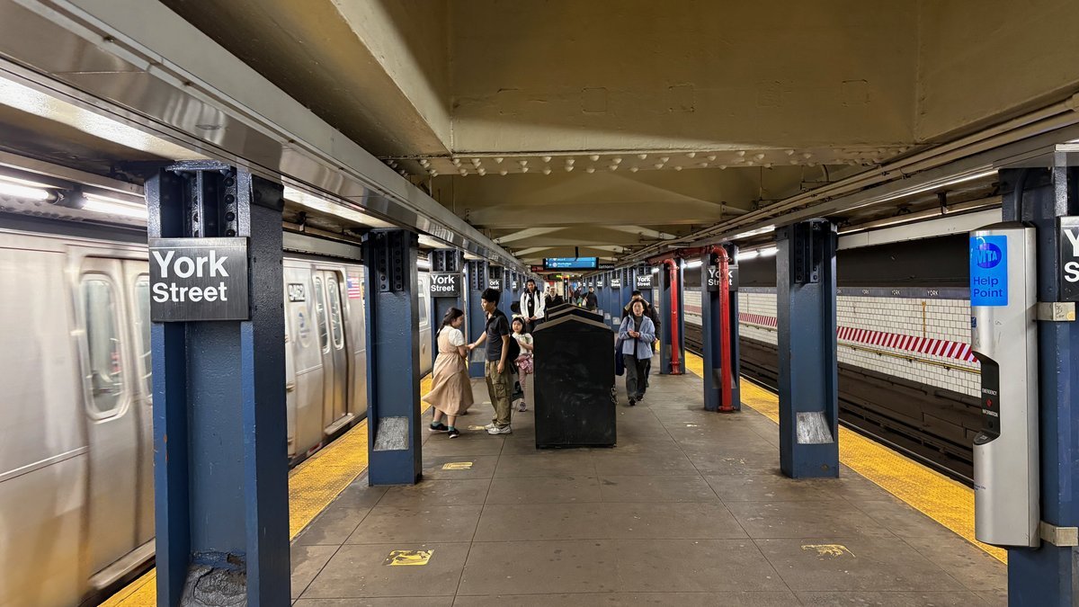 NYC subway platform with silver train and passengers boarding, public transit for day trip to Philadelphia from NYC