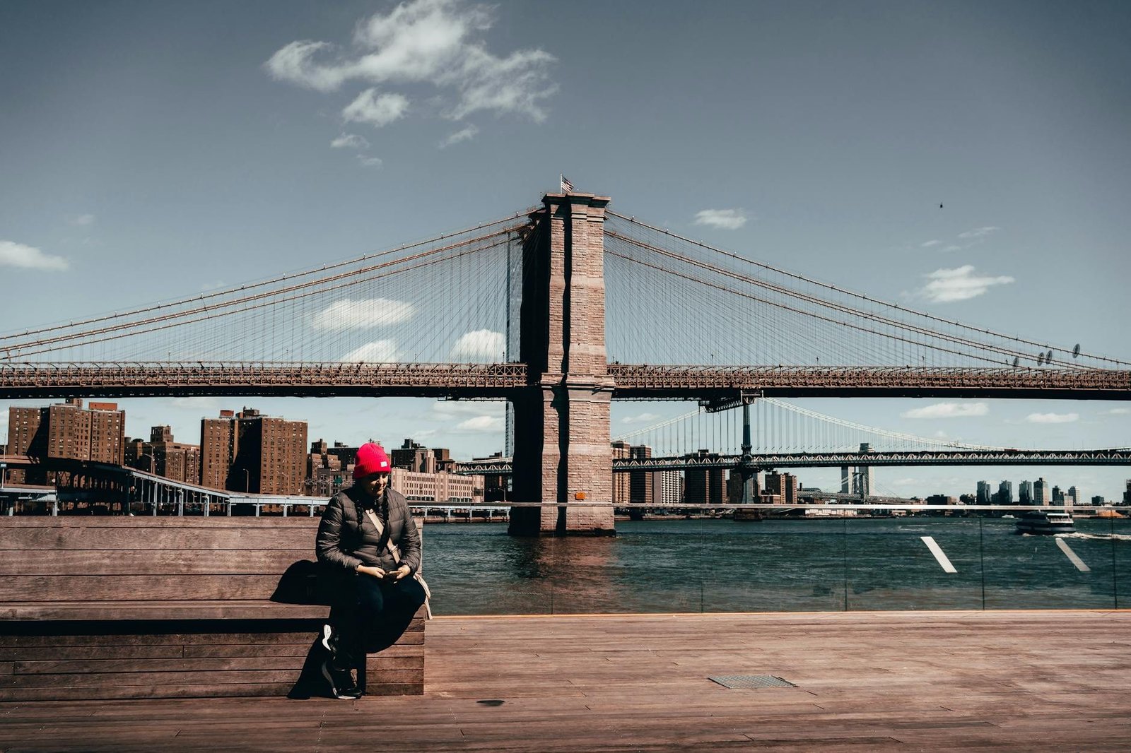 Vista del Puente de Brooklyn desde Brooklyn Bridge Park con una persona sentada.