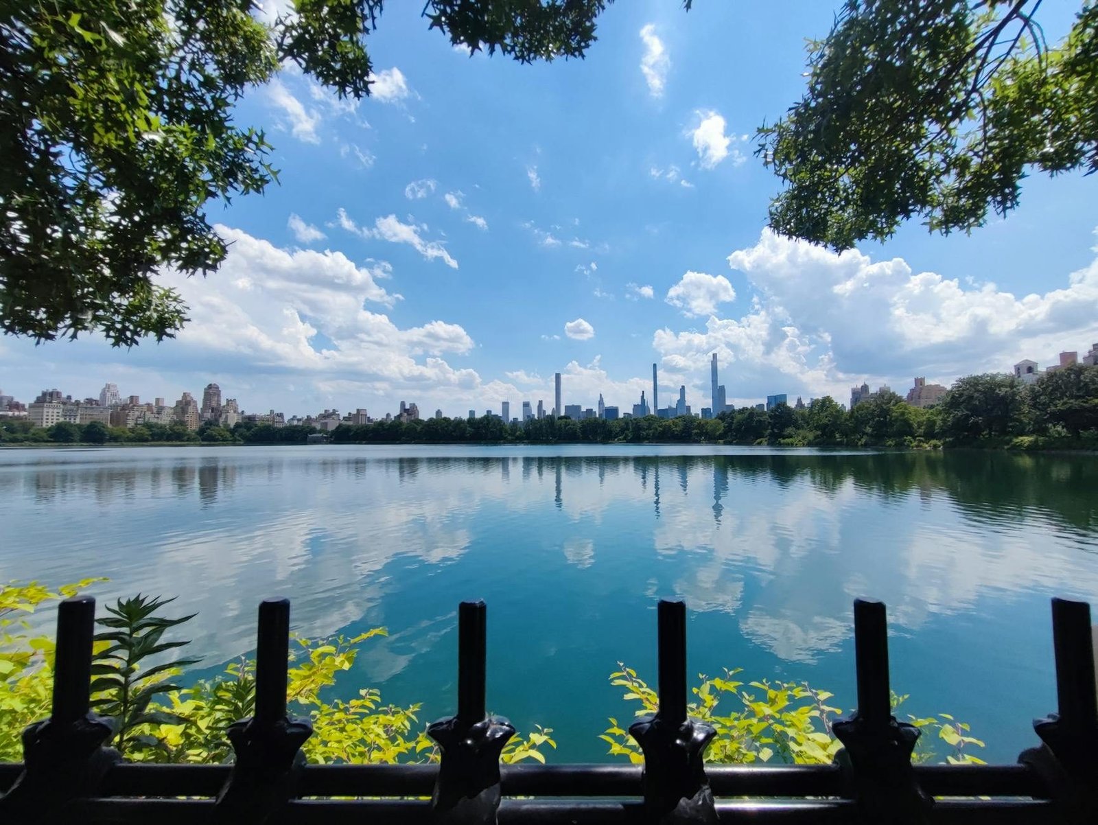 Central Park Reservoir view with Manhattan skyline reflection on a sunny day.