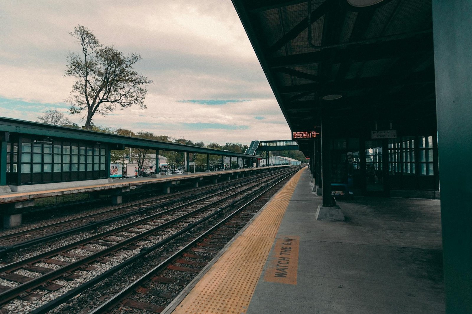 Metro-North train station platform and tracks under overcast sky, New York City transport.