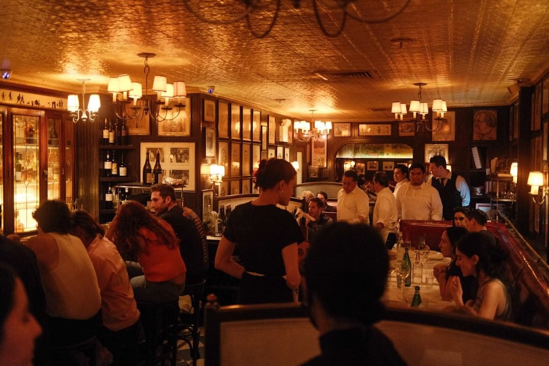Restaurante clásico de Nueva York con luz cálida, techo de hojalata y gente cenando.