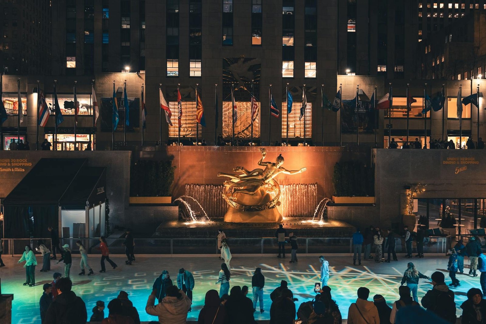 Rockefeller Center ice rink at night with Prometheus statue and skaters in Midtown Manhattan.