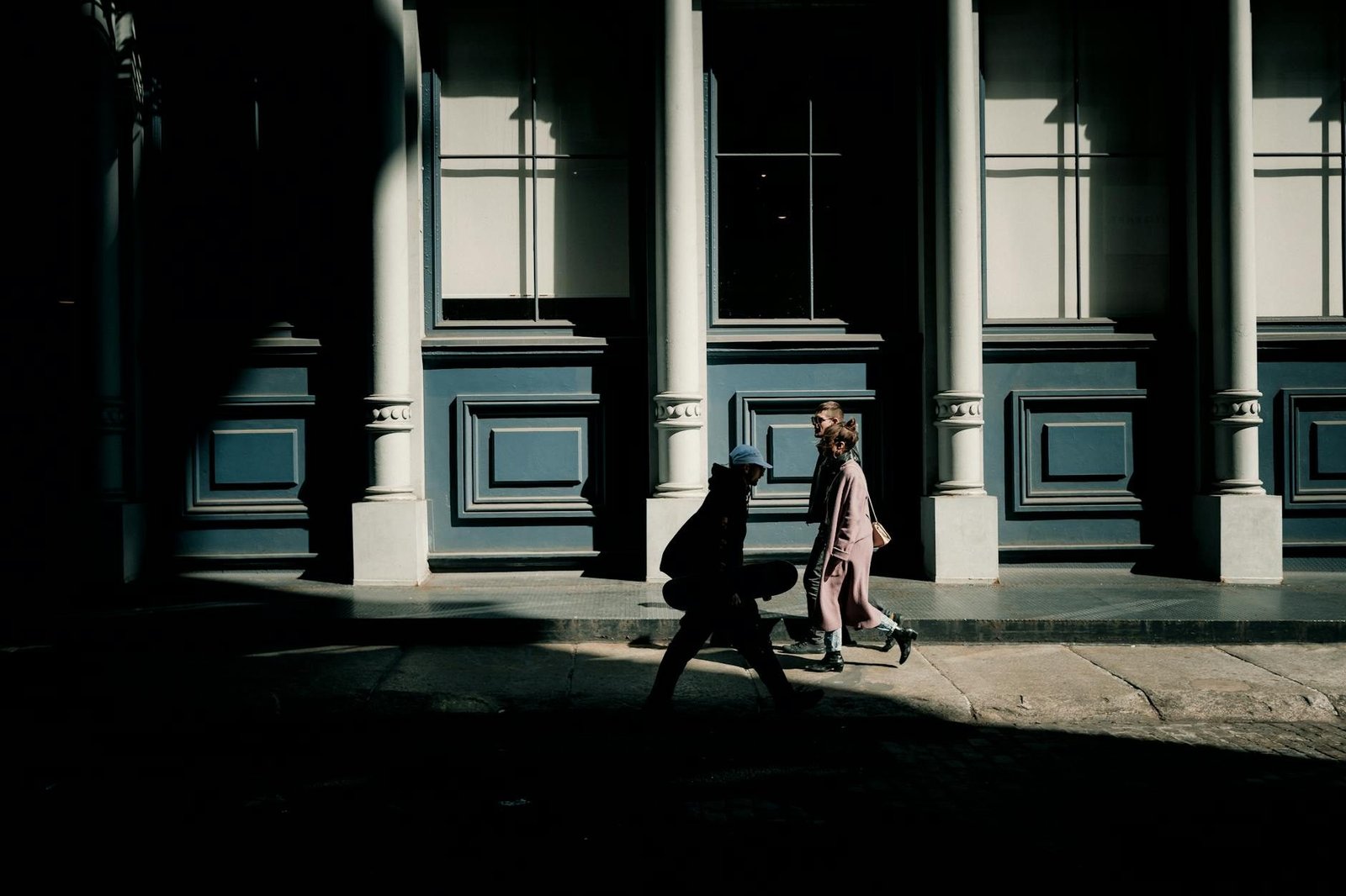 People walking on a sunny street in SoHo, New York City, with historic architecture.
