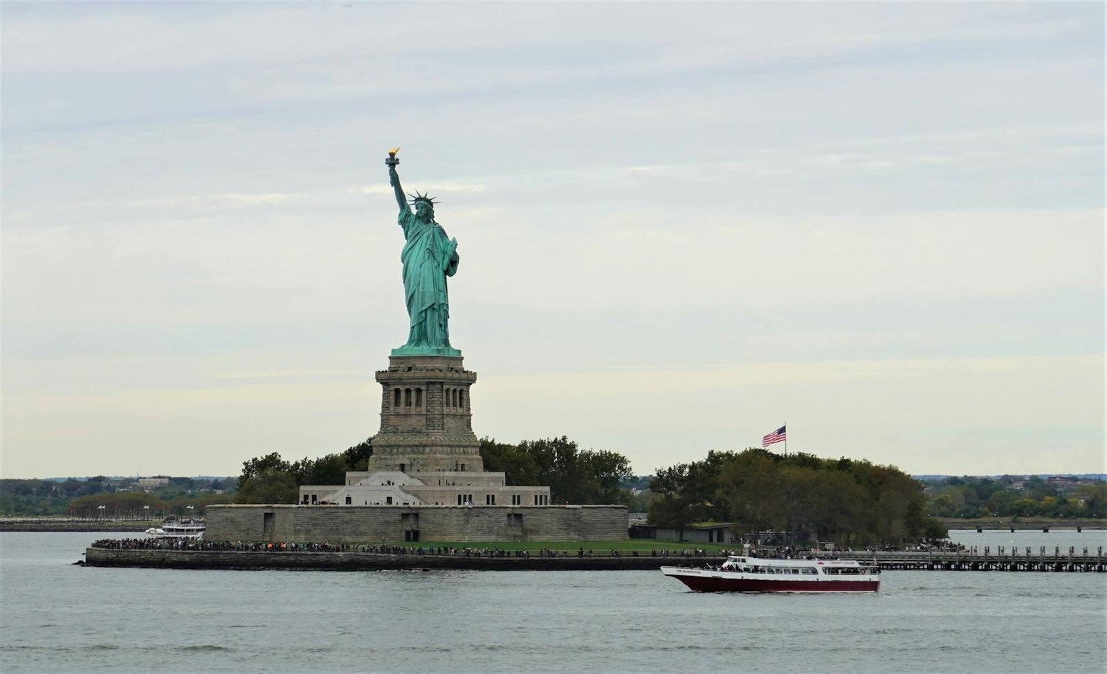 Statue of Liberty on Liberty Island, New York City, with a tour boat and flag.