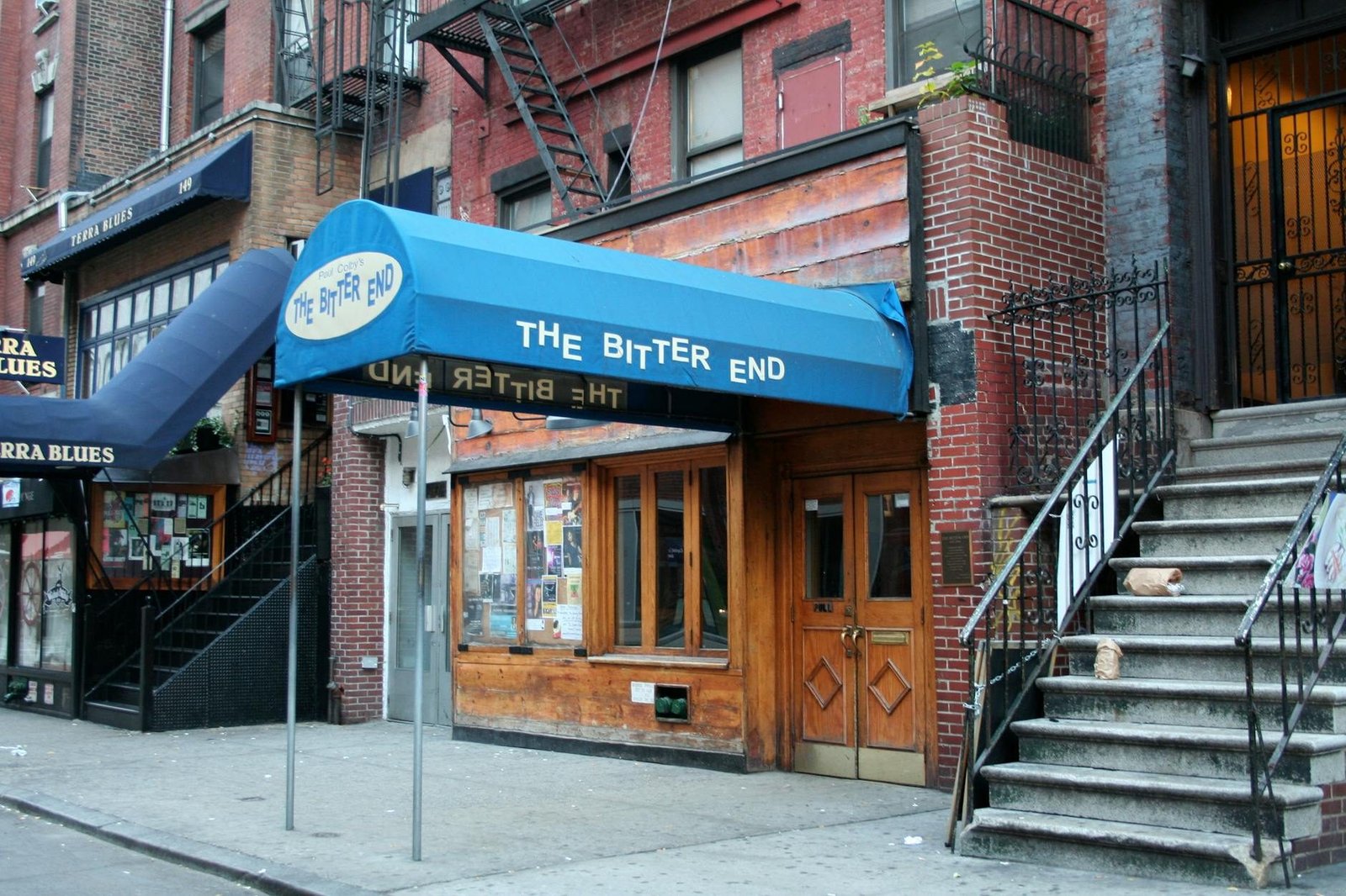 The Bitter End music club in Greenwich Village, NYC, with blue awning and brick facade.