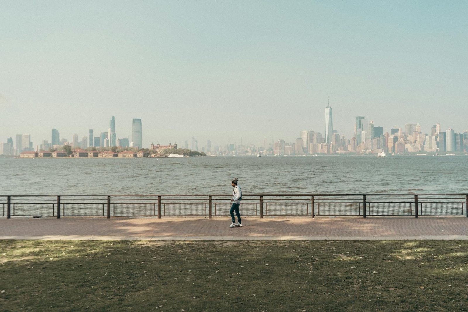Persona en paseo marítimo con vista al skyline de Lower Manhattan y Ellis Island.