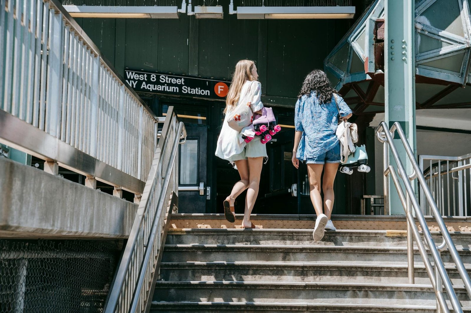 Women with roller skates climbing stairs at West 8 Street NY Aquarium F train station.