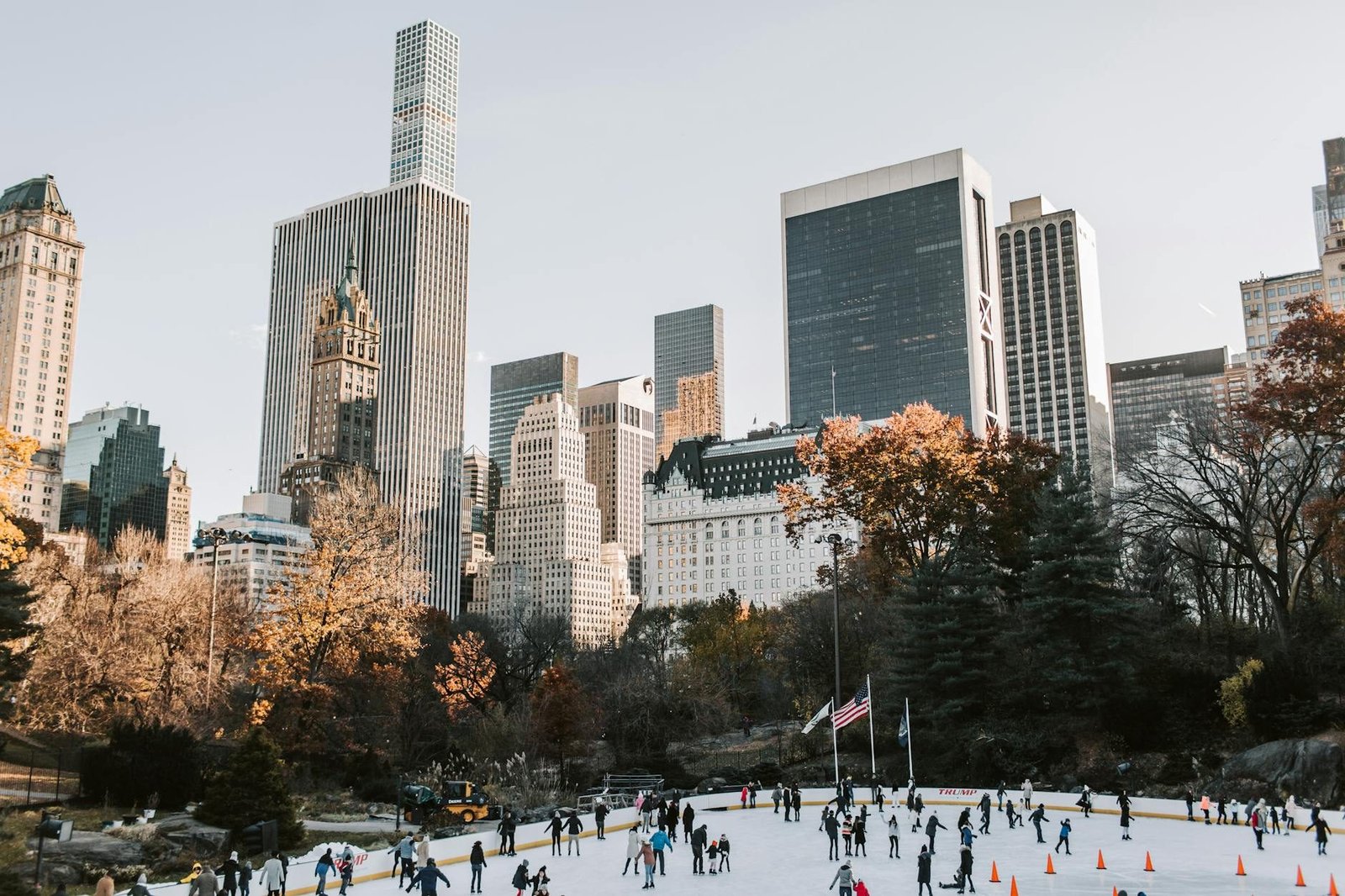 Wollman Rink Central Park ice skating, vibrant autumn trees, and iconic Manhattan skyline.